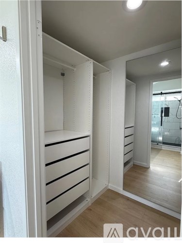 A white walk-in closet with shelves and a mirror.