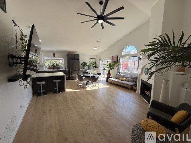 A living room with a television, a couch, and a ceiling fan.