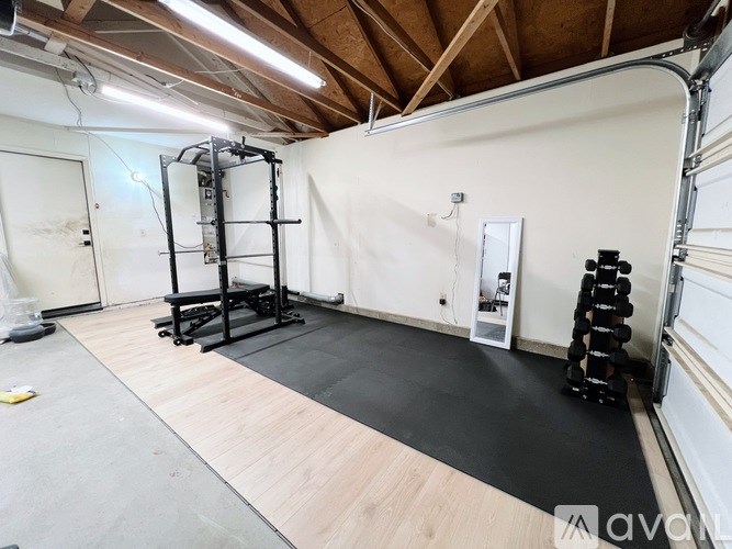 A gym with a weight rack, bench, and dumbbells.