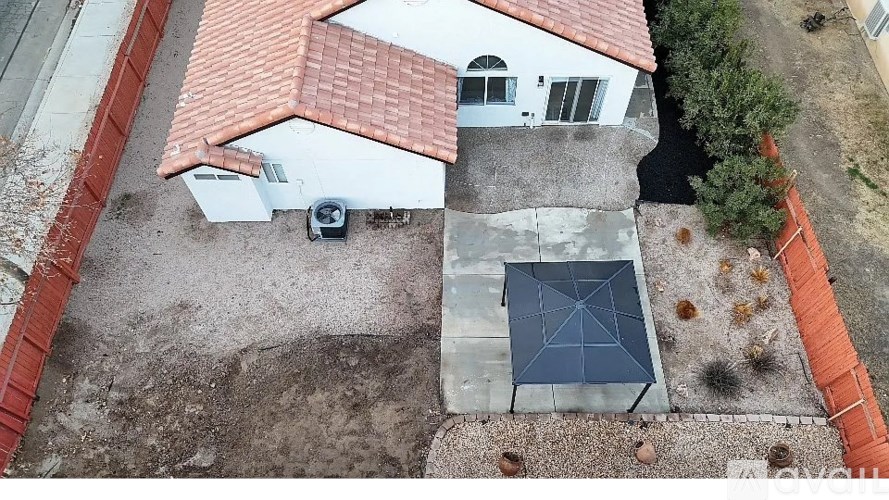 A house with a red tile roof and a white exterior is shown from an aerial perspective.