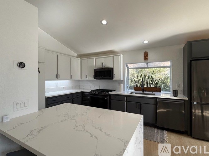 A kitchen with a marble countertop and black appliances.