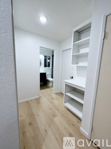 A white shelving unit in a room with wooden flooring.