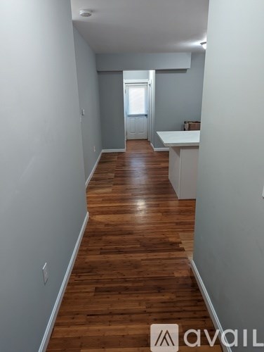 A long hallway with wood floors and white walls.