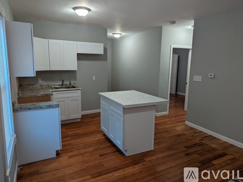 A kitchen with white cabinets and a wooden floor.