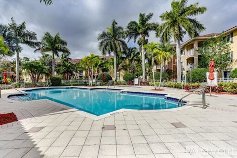 A swimming pool surrounded by palm trees and a red sculpture.