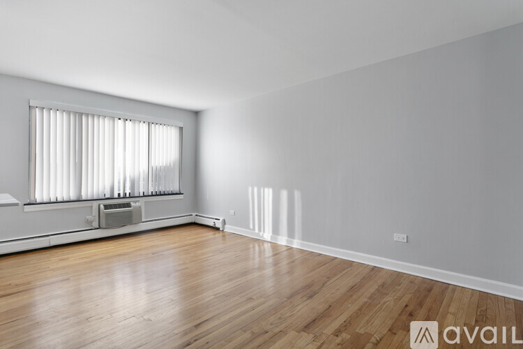 A room with wooden floors and a window with blinds.