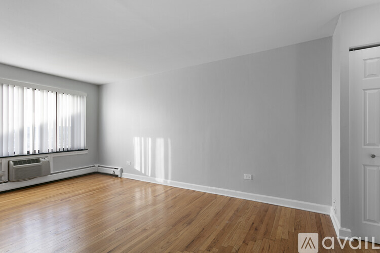 A room with wooden floors and a window with blinds.
