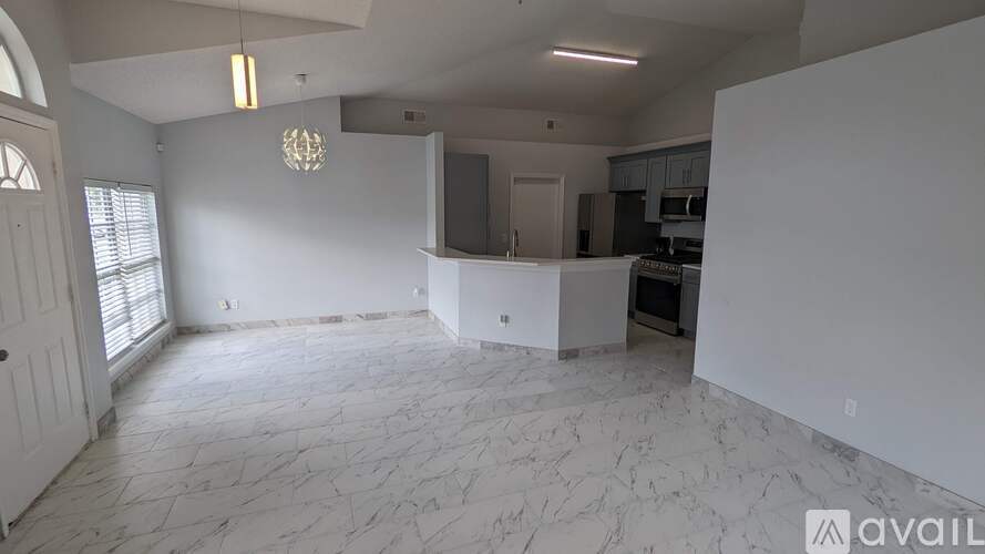 A spacious living room with marble flooring and a chandelier.