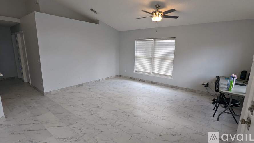 A room with a ceiling fan and a window with blinds.