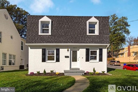 A white house with a black roof and a sign that says "available" in front of it.