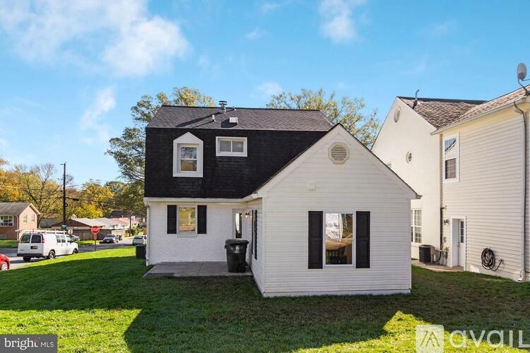 A house with a black roof and white walls is for sale.