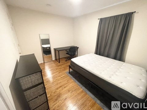 A bedroom with a bed, desk, and chair.