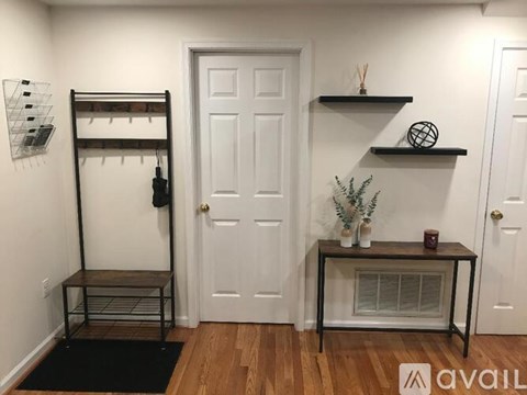 A room with a white door, a shelf with a plant, and a black table with a candle on it.