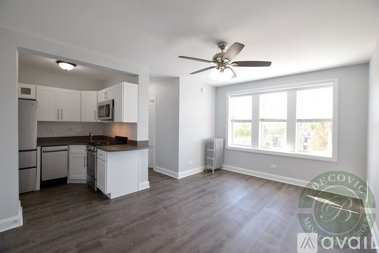 A well-lit, spacious kitchen and living room with a wood floor and white walls.