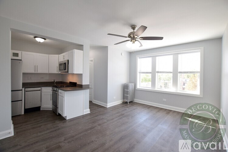 A well-lit, spacious kitchen and living room with a wood floor and white walls.