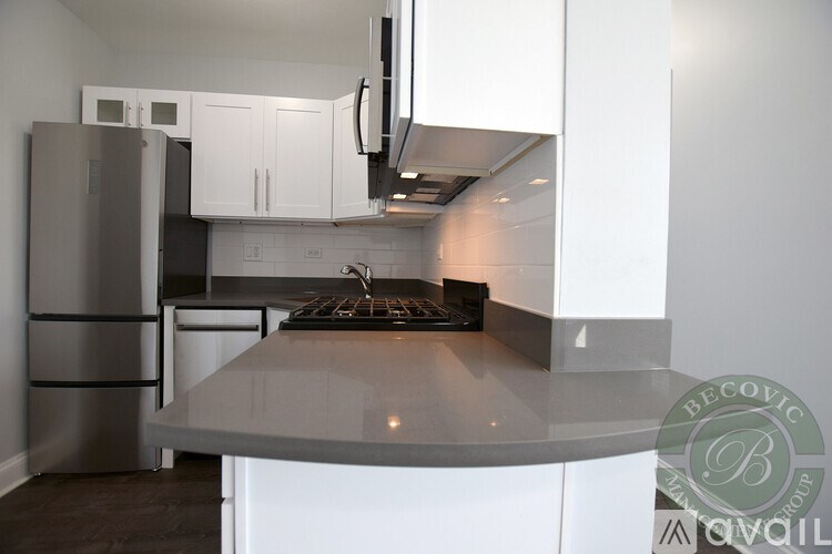 A modern kitchen with white cabinets and a stainless steel refrigerator.