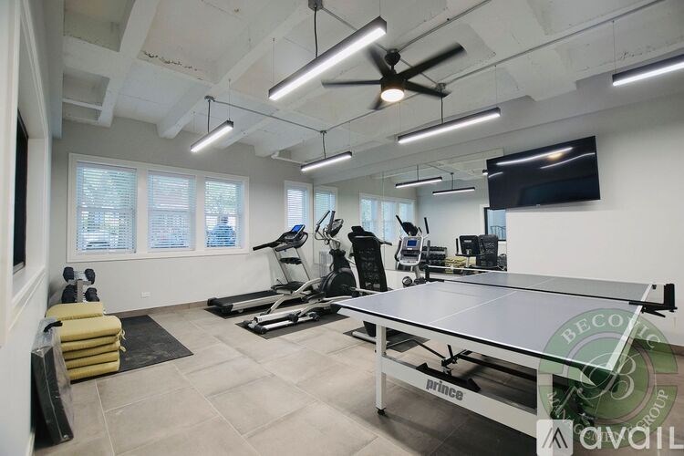 A room with a ping pong table, treadmills, and exercise equipment.