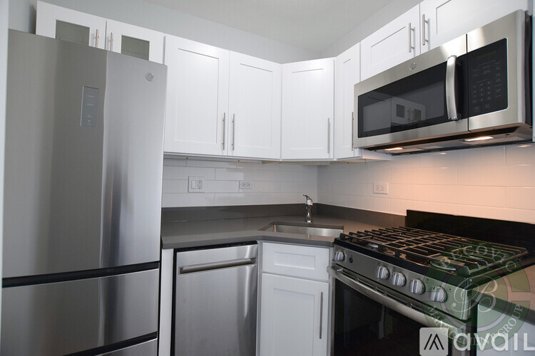A kitchen with a stainless steel refrigerator, white cabinets, and a black stove top.