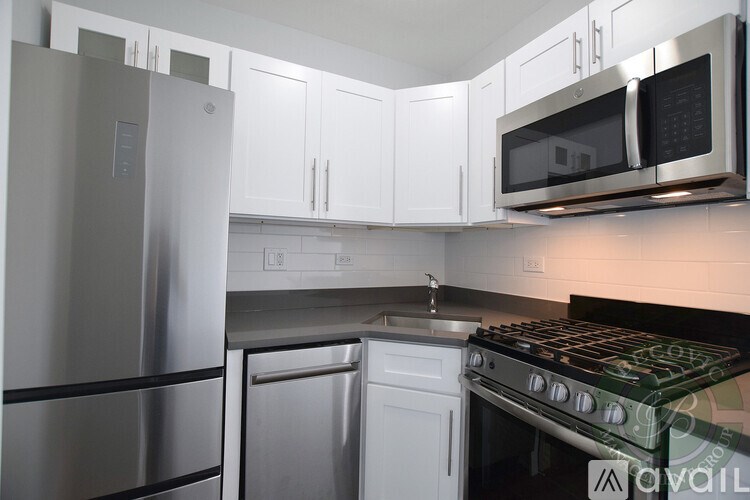 A kitchen with a stainless steel refrigerator, white cabinets, and a black stove top.