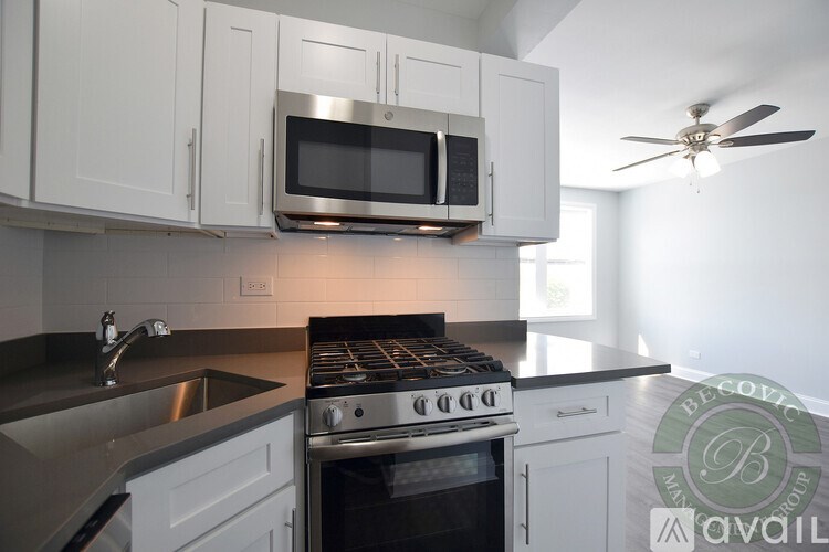 A modern kitchen with a stove, microwave, and a fan.