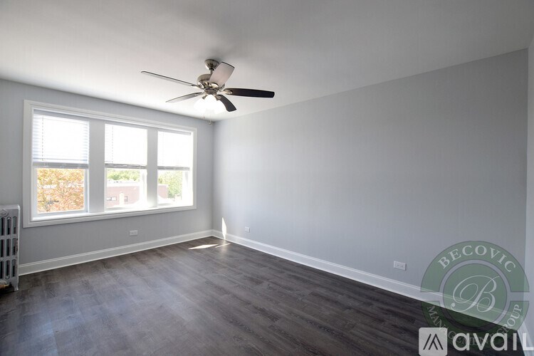 A room with a ceiling fan and a window with a view of trees.
