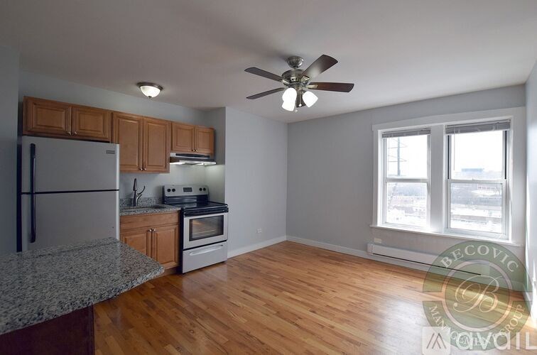 A kitchen with a refrigerator, oven, and a ceiling fan.