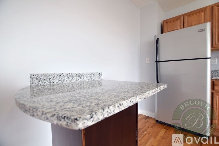 A kitchen counter with a granite top and a refrigerator in the background.