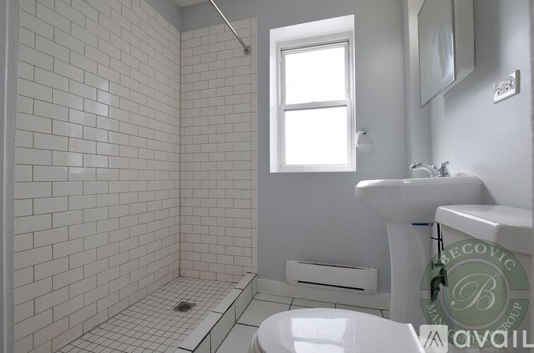 A white tiled bathroom with a window and a sink.