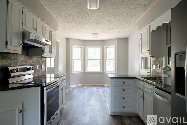 A kitchen with white cabinets and a black countertop.