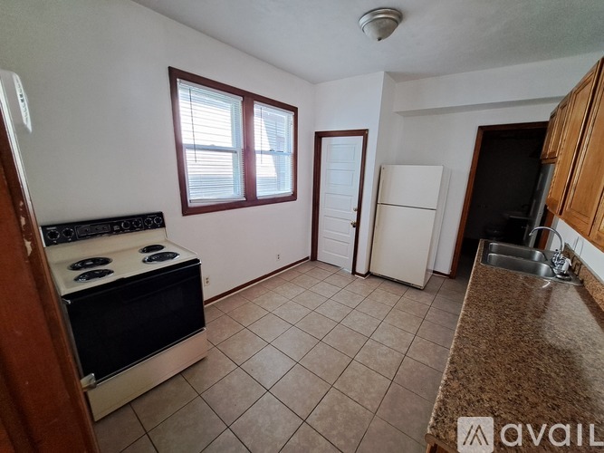 A kitchen with a stove, sink, and refrigerator.