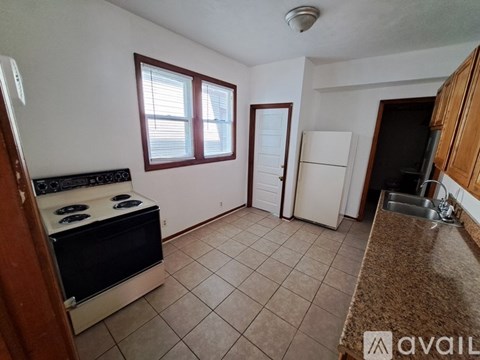 A kitchen with a stove, sink, and refrigerator.