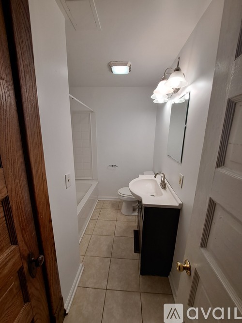 A bathroom with a toilet, sink, and mirror.
