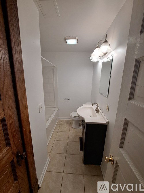 A bathroom with a toilet, sink, and mirror.