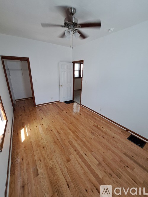 A room with wooden flooring and a ceiling fan.