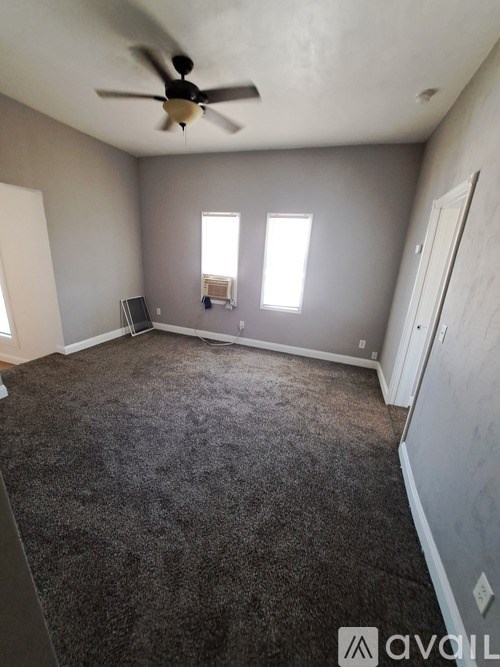 A room with a ceiling fan and carpeted floor.