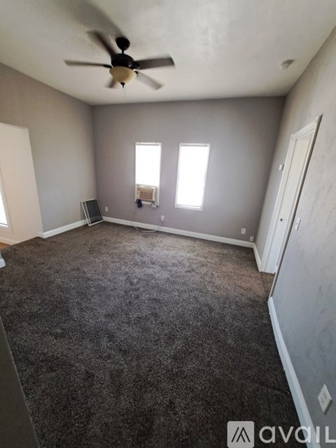 A room with a ceiling fan and carpeted floor.