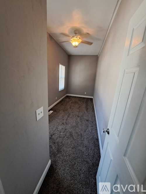 A room with a ceiling fan and carpeted floor.