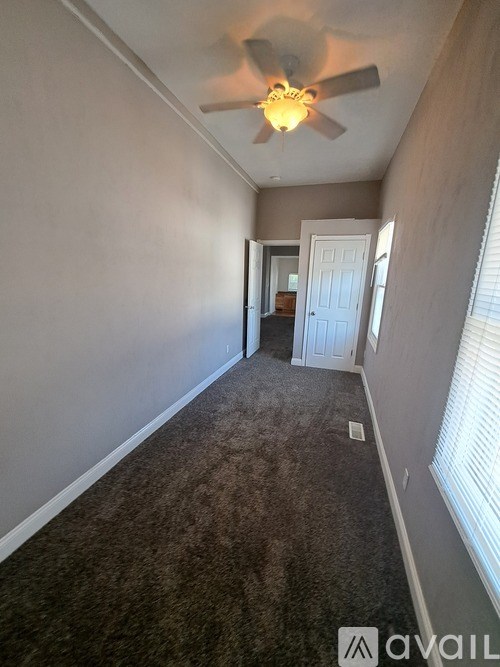 A room with a carpeted floor and a ceiling fan.