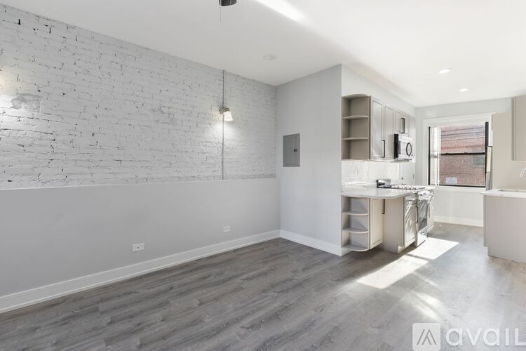 A spacious room with a white brick wall and wooden flooring.