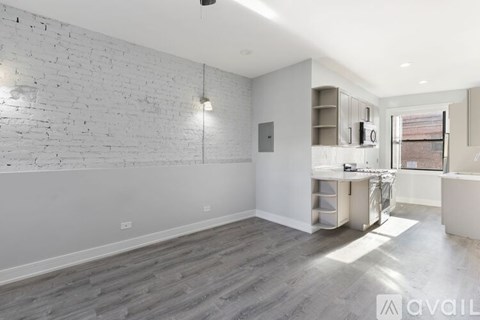 A spacious room with a white brick wall and wooden flooring.