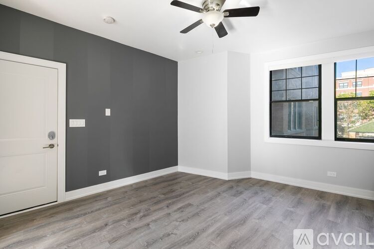 A room with a ceiling fan and a window with a view of a building outside.