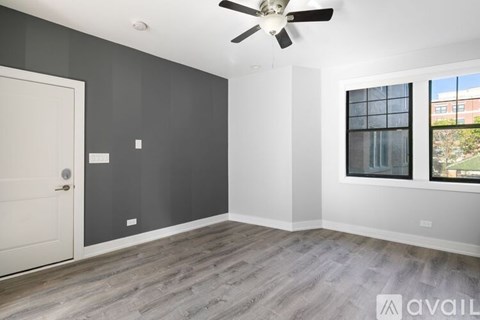 A room with a ceiling fan and a window with a view of a building outside.