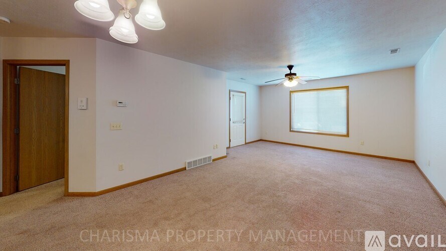 A spacious room with a carpeted floor and a ceiling fan.