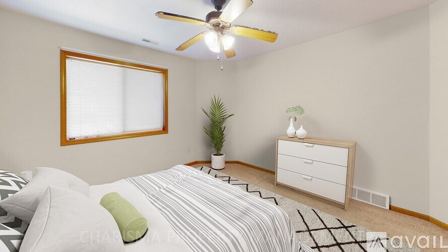 A bedroom with a bed, a ceiling fan, and a nightstand.