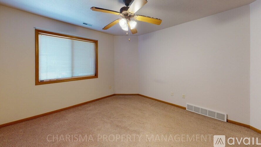 A room with a ceiling fan and a window with blinds.