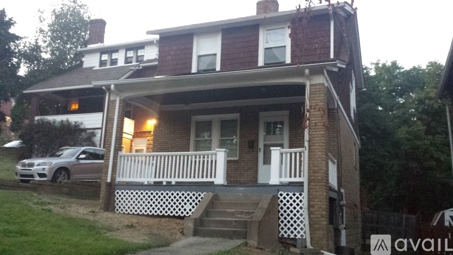 A house with a porch and a car parked in front.