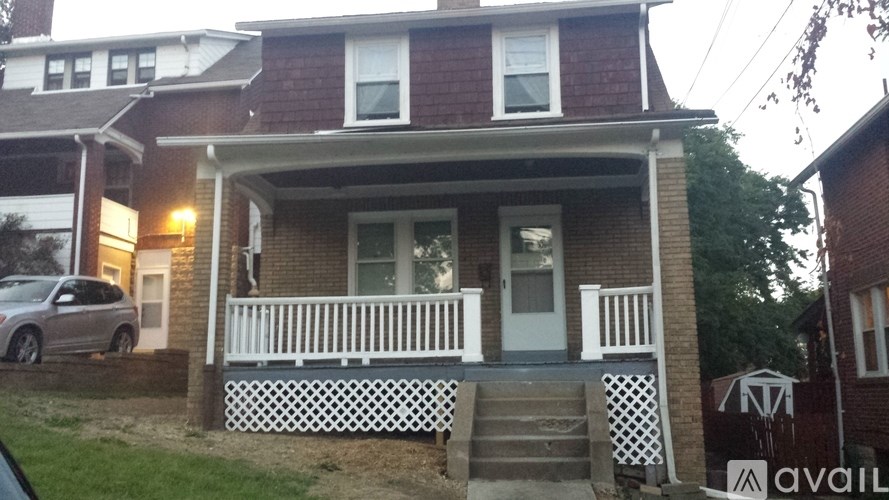 A house with a white porch and a car parked in front.