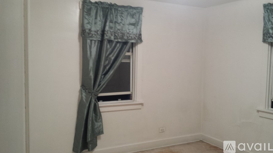 A window with a green curtain tied in a bow.