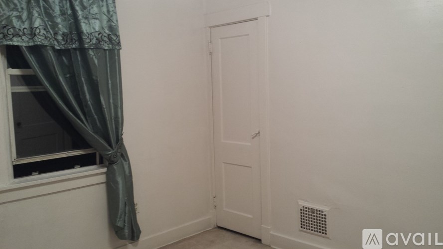 A room with a door, a window with a curtain, and a wall heater.