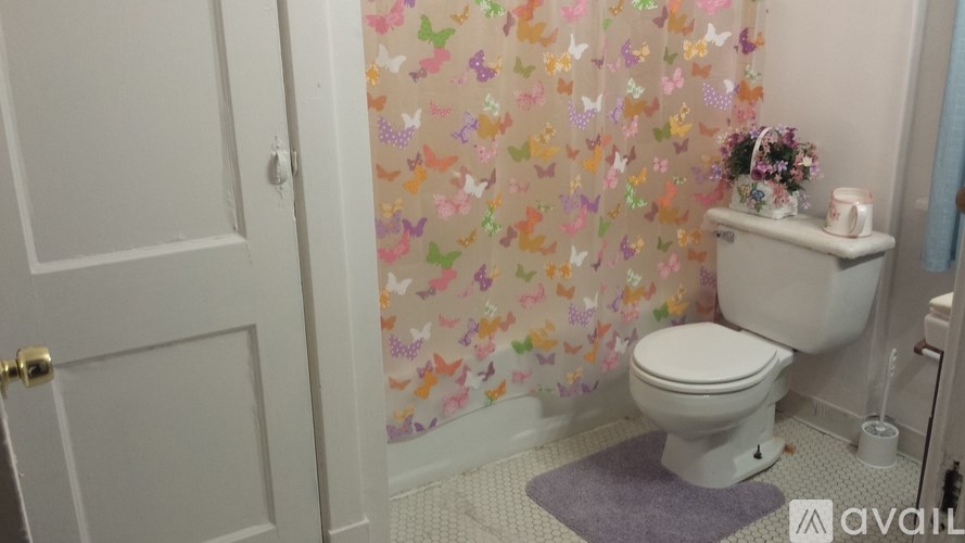A white toilet in a bathroom with a floral shower curtain.